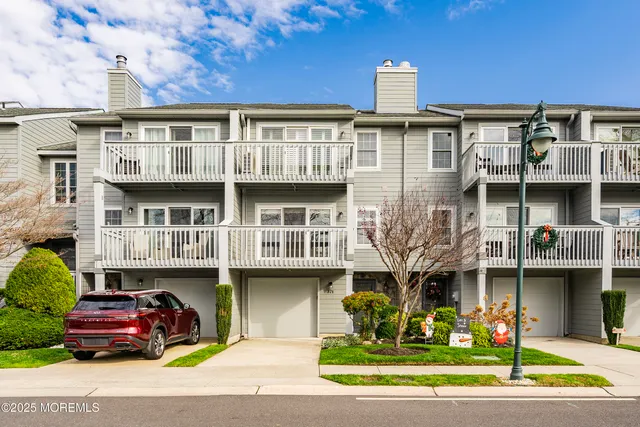 a front view of a building with garden and parking