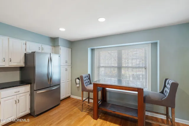 a kitchen with granite countertop a refrigerator cabinets dining table and chairs