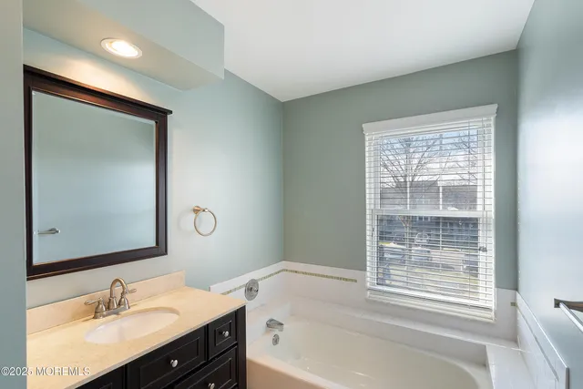 a bathroom with a bathtub sink vanity and mirror
