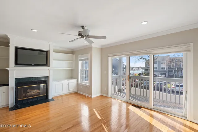 a view of a livingroom with a fireplace a ceiling fan and windows
