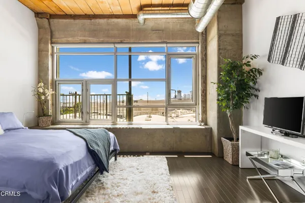a bedroom with a bed and a flat tv screen next to a window