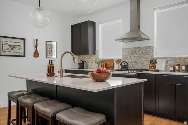 493 East Alice Way Layton, UT 84041 - Photo 1 of 31 Kitchen featuring light wood-style floors, a breakfast bar area, a center island with sink, light stone countertops, and decorative light fixtures
