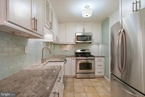 a kitchen with granite countertop a stove top oven microwave and cabinets