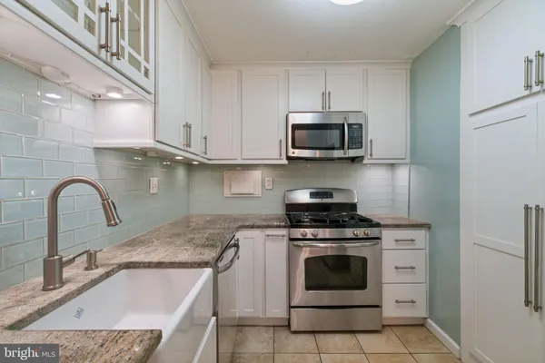 a kitchen with stainless steel appliances white cabinets white stove a microwave and a refrigerator