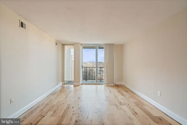 a view of an empty room with wooden floor and a window
