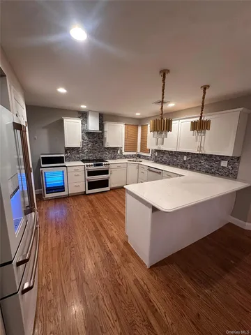 a large kitchen with stainless steel appliances granite countertop a lot of counter space and wooden floor