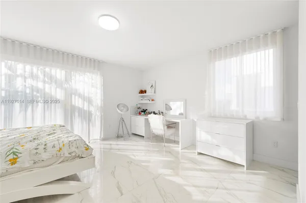 a large white kitchen with kitchen island a sink and a large window