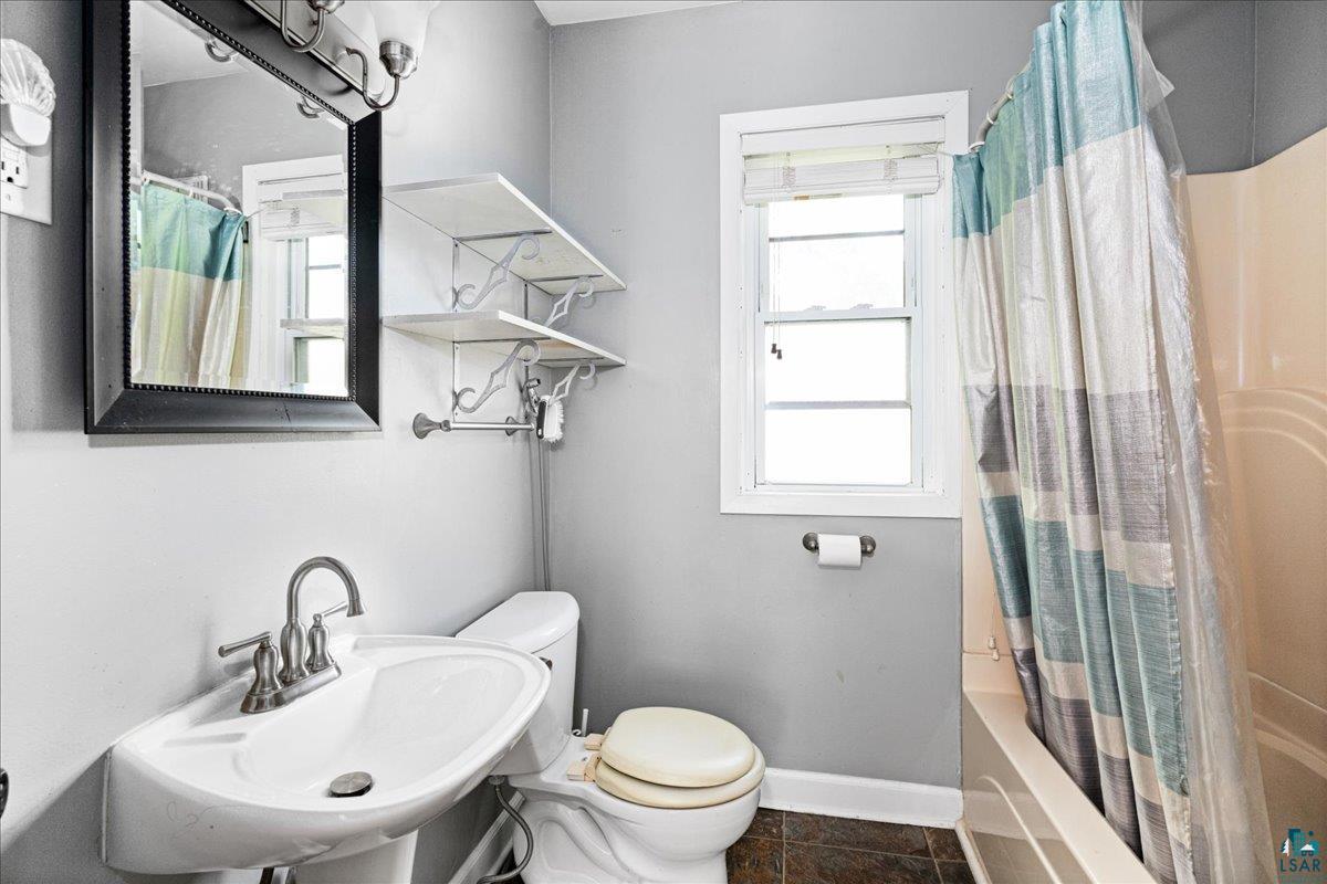 519 3rd Avenue Proctor, MN 55810 - Photo 14 of 25 Full bathroom with tile patterned flooring, plenty of natural light, toilet, and shower / bath combination with curtain