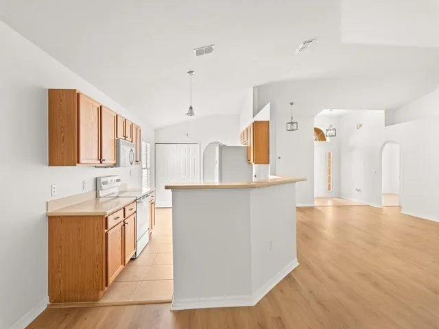 a large kitchen with stainless steel appliances a large counter top a stove and a refrigerator