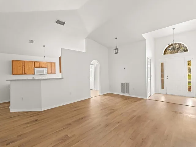 a view of empty room with window and wooden floor