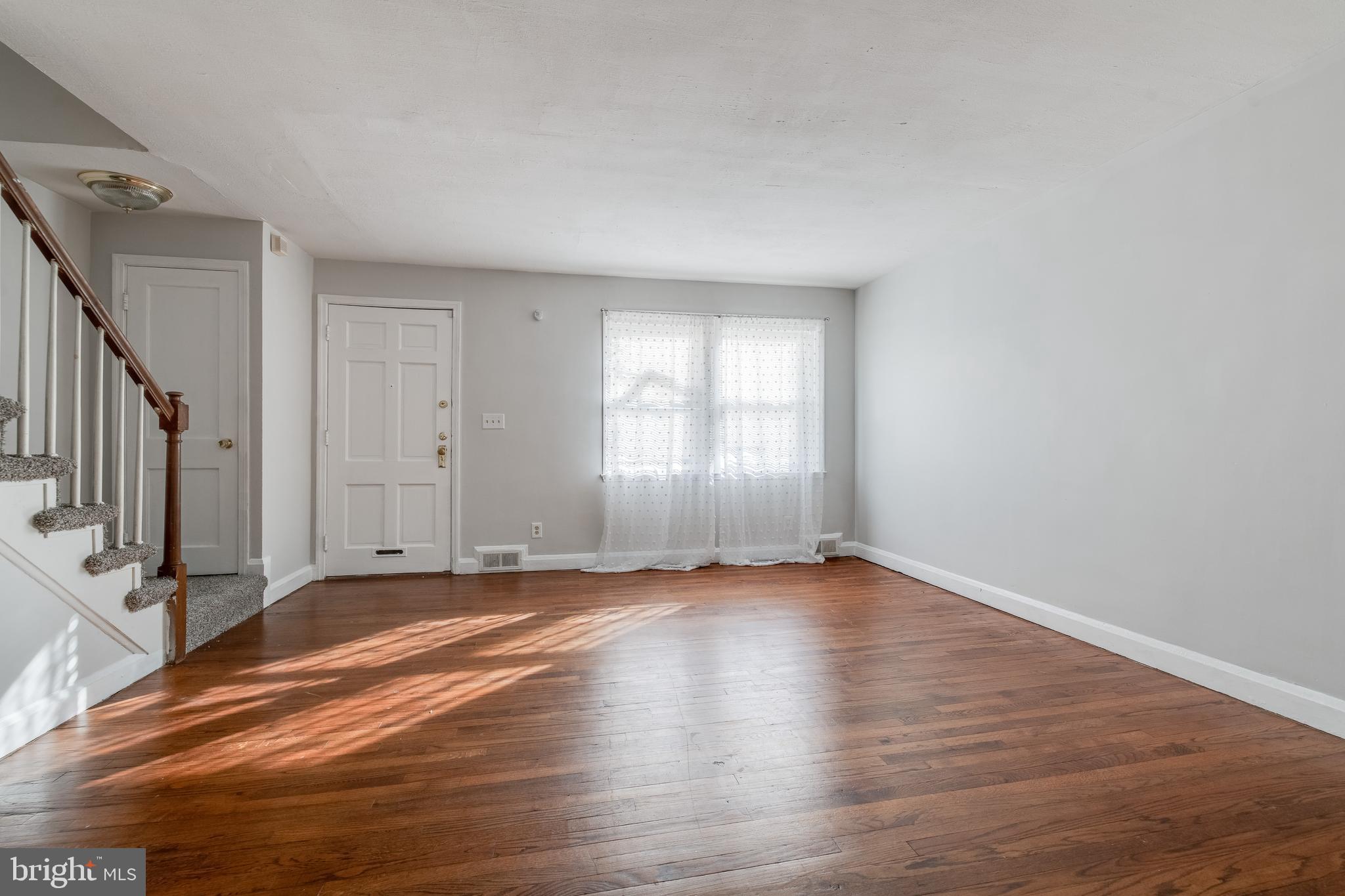 1306 East Cold Spring Lane Baltimore, MD 21239 - Photo 2 of 25 a view of an empty room with wooden floor and a window