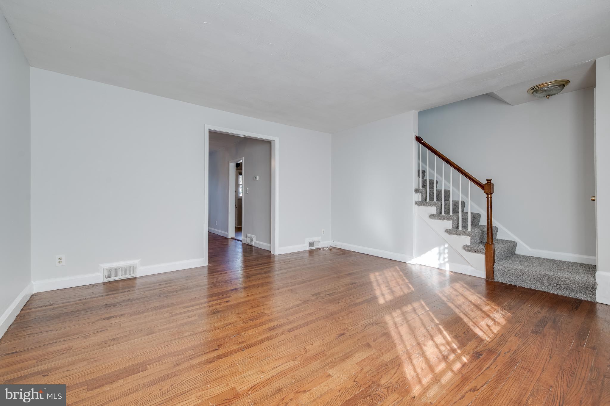 1306 East Cold Spring Lane Baltimore, MD 21239 - Photo 4 of 25 a view of an empty room with wooden floor and stairs
