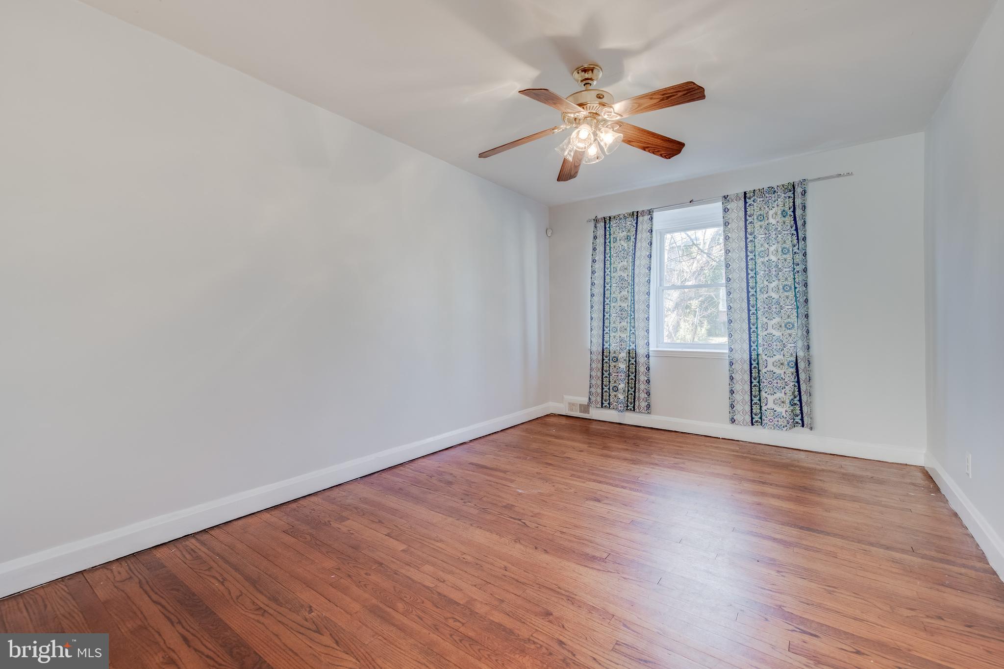 1306 East Cold Spring Lane Baltimore, MD 21239 - Photo 5 of 25 a view of an empty room with wooden floor and a window