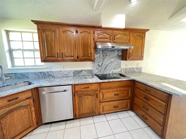 a kitchen with granite countertop a sink stove and cabinets