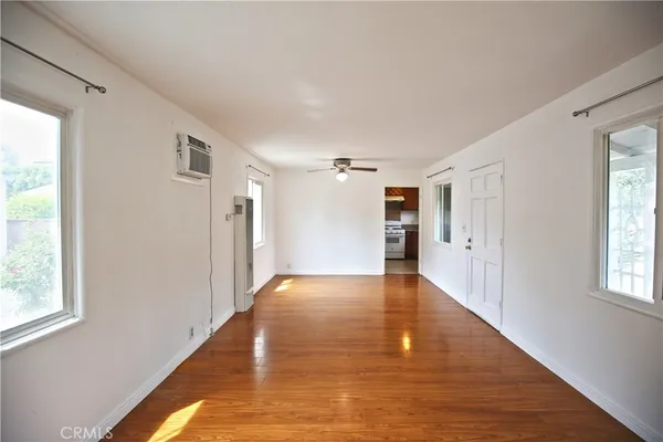 a view of a hallway with wooden floor and a bathroom