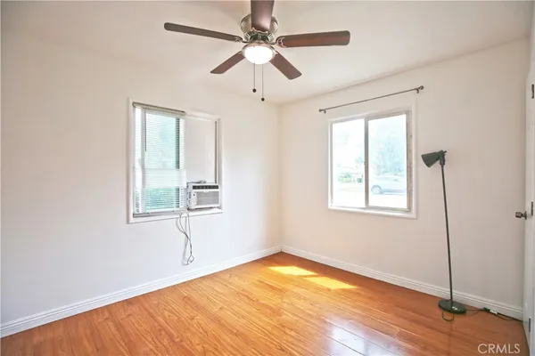 a view of empty room with wooden floor and fan