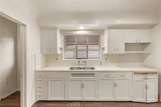 a kitchen with white cabinets and window