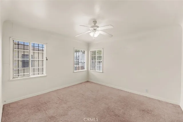 an empty room with chandelier fan and windows