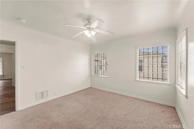 an empty room with windows and fan