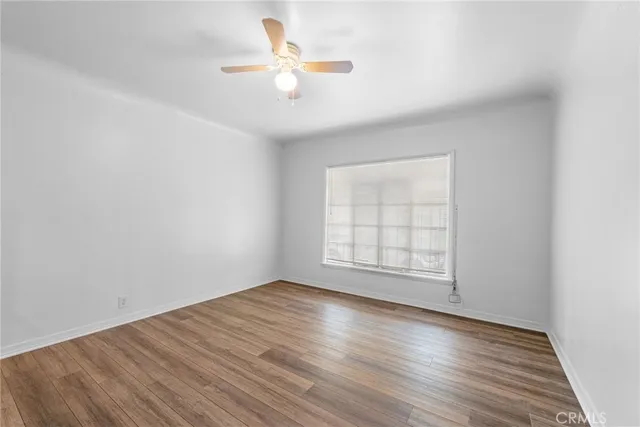 an empty room with wooden floor chandelier fan and windows