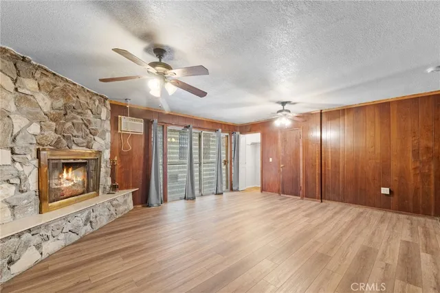 a view of an empty room with a fireplace and a ceiling fan