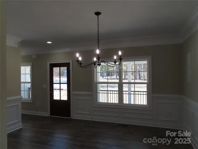 a view of an empty room with wooden floor and windows