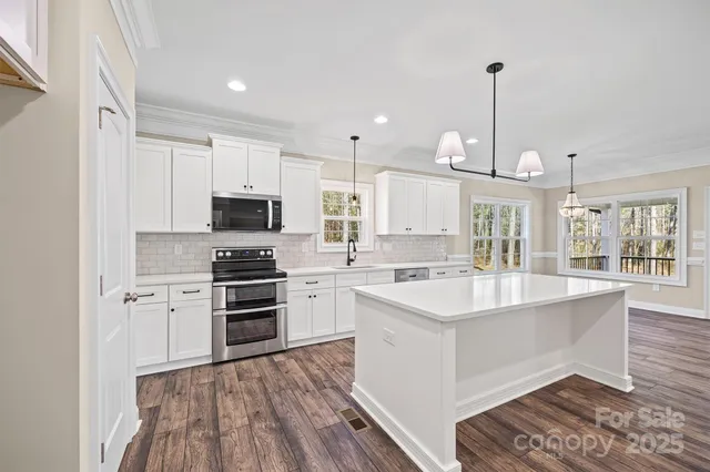 a large white kitchen with kitchen island white cabinets and stainless steel appliances
