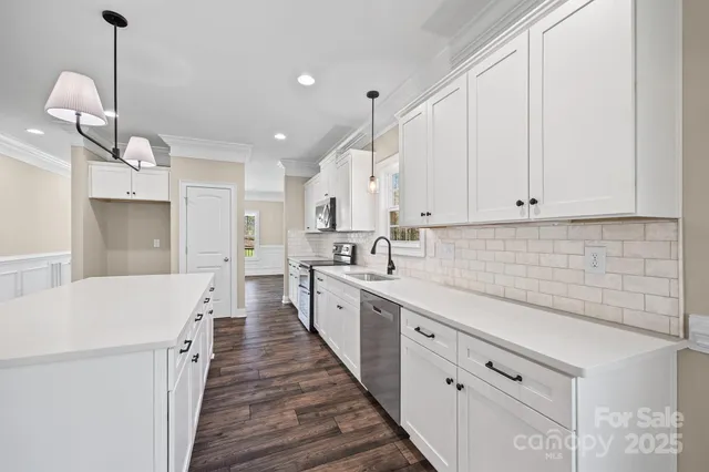 a large white kitchen with sink and cabinets