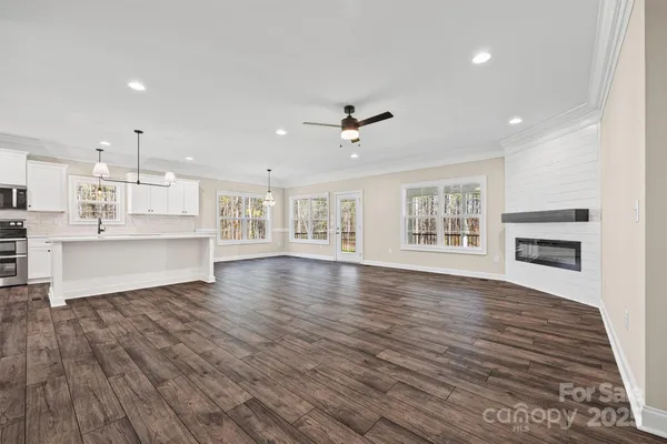 an empty room with wooden floor chandelier and windows