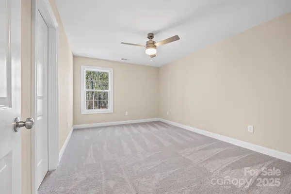 an empty room with a chandelier fan and windows