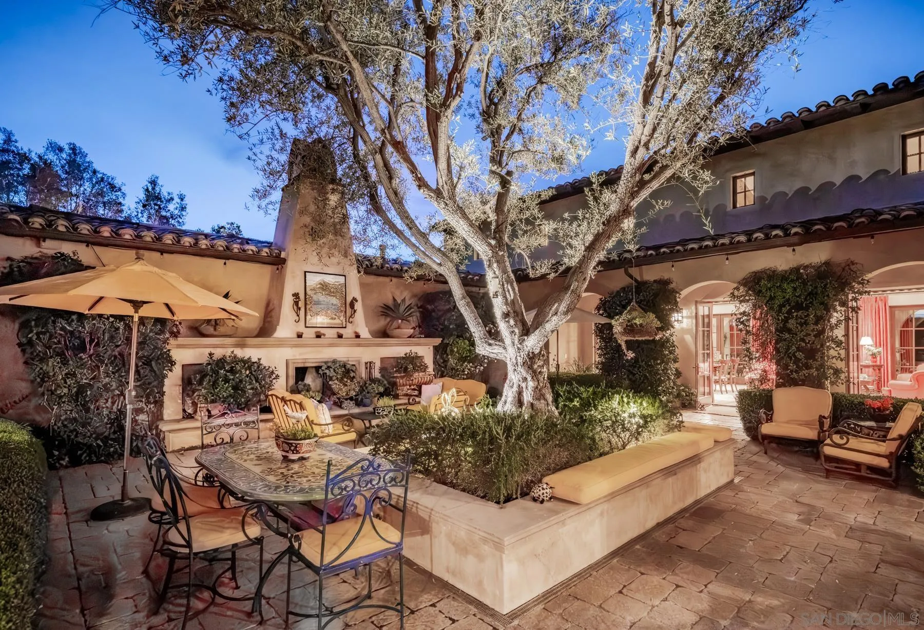 18669 Via Catania Rancho Santa Fe, CA 92091 - Photo 2 of 39 a view of a patio with table and chairs with potted plants and a large tree