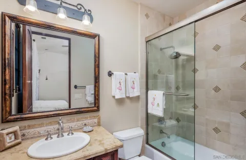 a bathroom with a granite countertop shower sink mirror and toilet