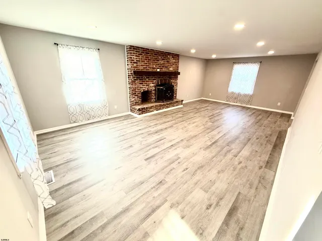 an empty room with windows and fireplace