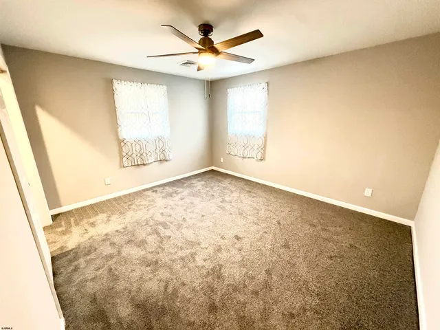 an empty room with windows and ceiling fan