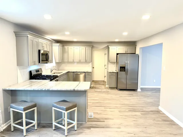 a large kitchen with kitchen island granite countertop a sink and a refrigerator
