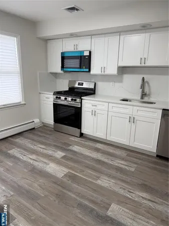 a kitchen with granite countertop a stove a sink and a microwave