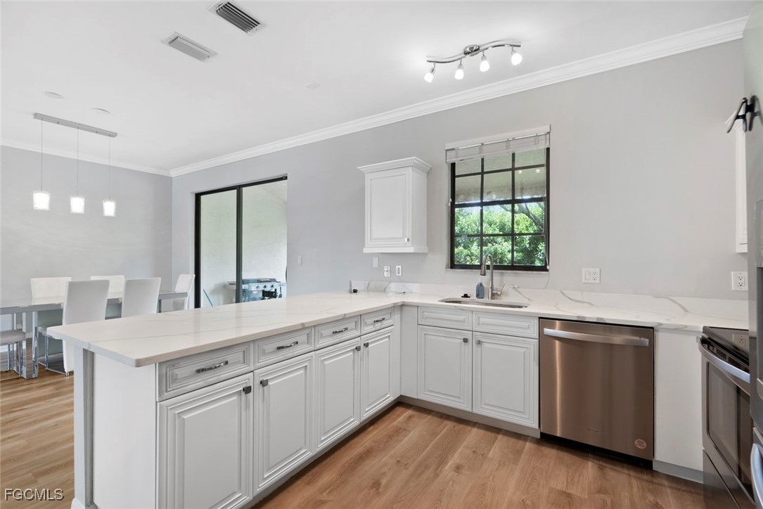 14617 Sutherland Avenue, Unit 80 Naples, FL 34119 - Photo 11 of 46 a kitchen with a sink dishwasher a stove and white cabinets with wooden floor
