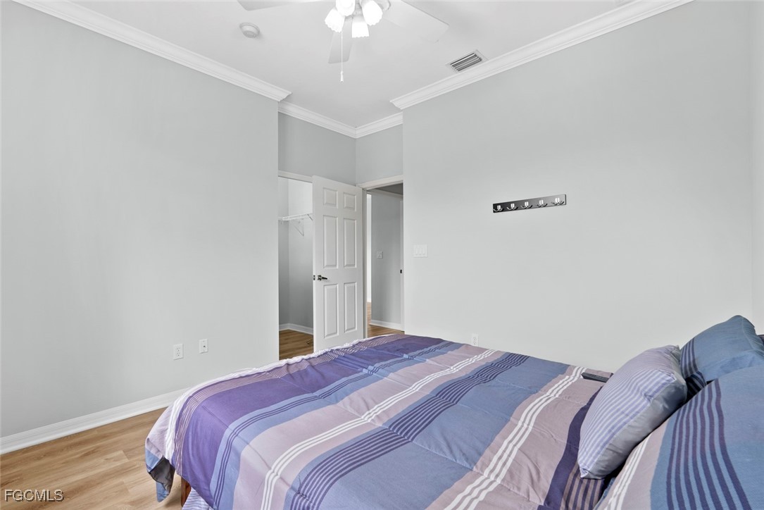 14617 Sutherland Avenue, Unit 80 Naples, FL 34119 - Photo 22 of 46 a bedroom with a bed and a chandelier fan