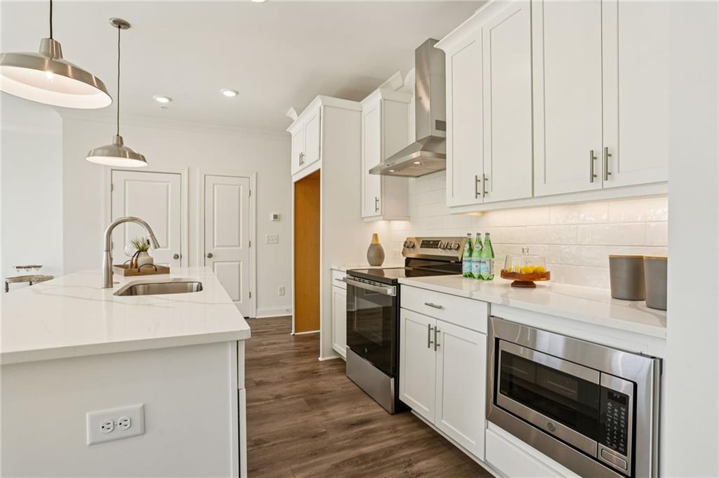 532 Alice Way, Unit D8 Cumming, GA 30040 - Photo 16 of 40 a kitchen with stainless steel appliances a stove a sink and white cabinets