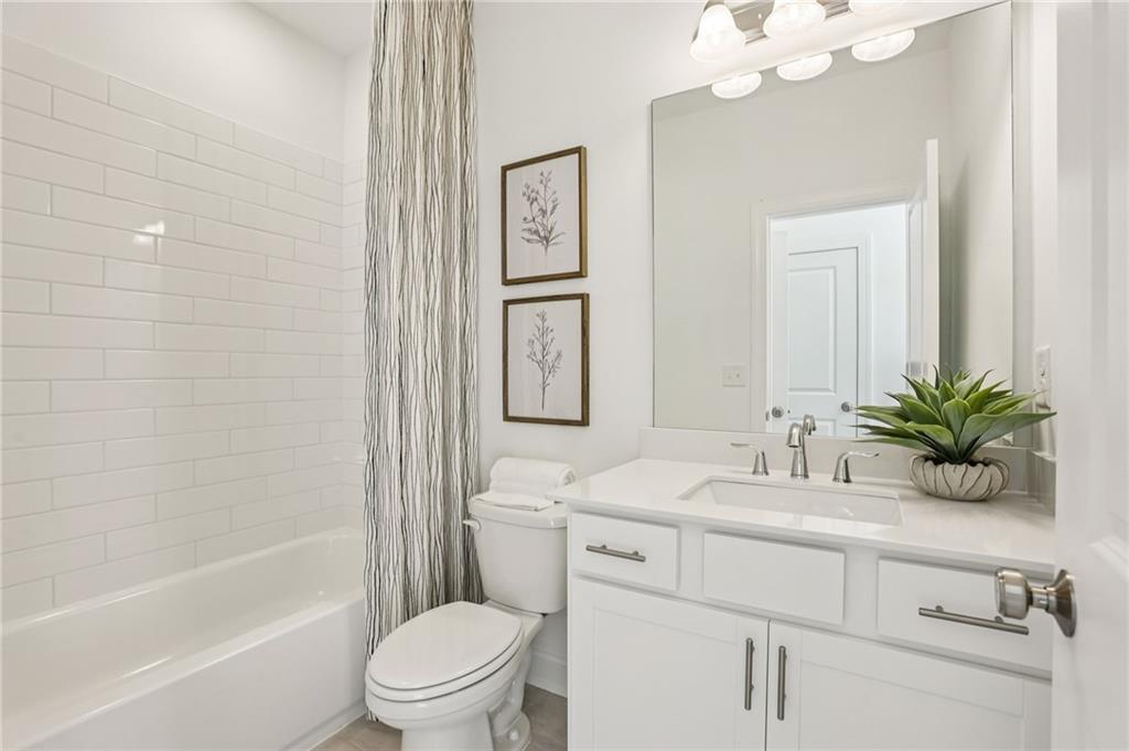 532 Alice Way, Unit D8 Cumming, GA 30040 - Photo 34 of 40 a bathroom with a granite countertop sink a toilet a mirror a vanity a vanity and shower