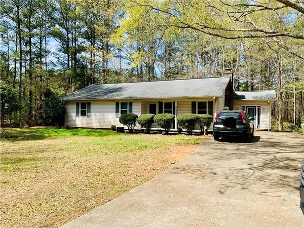 a front view of a house with a yard and large trees
