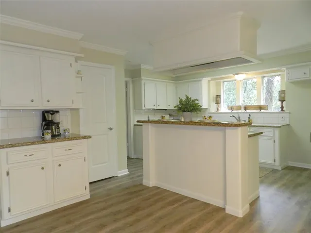a kitchen with kitchen island granite countertop a sink and cabinets