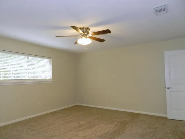 an empty room with a window and a fan