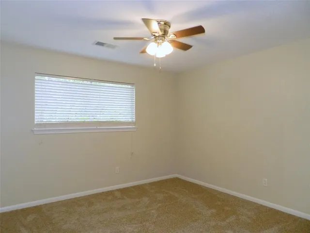 an empty room with a window and a ceiling fan