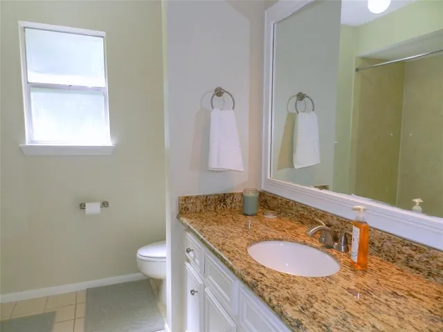 a bathroom with a granite countertop double vanity sink mirror and toilet