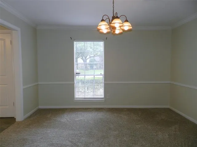 an empty room with a chandelier fan and windows