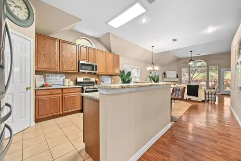 a kitchen with stainless steel appliances a refrigerator a stove a sink dishwasher and a dining table with wooden floor
