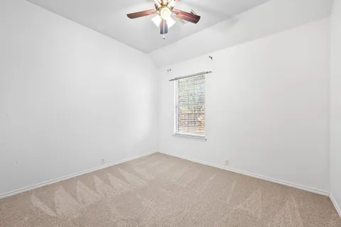 an empty room with a chandelier fan and windows