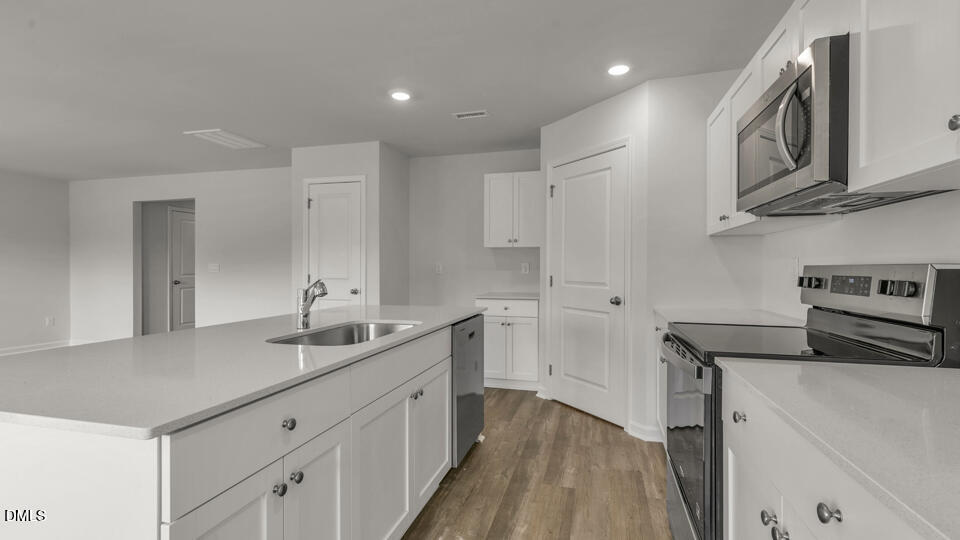 629 Stream Walk Crossing Wendell, NC 27591 - Photo 10 of 38 a kitchen with a sink dishwasher a refrigerator and white cabinets with wooden floor