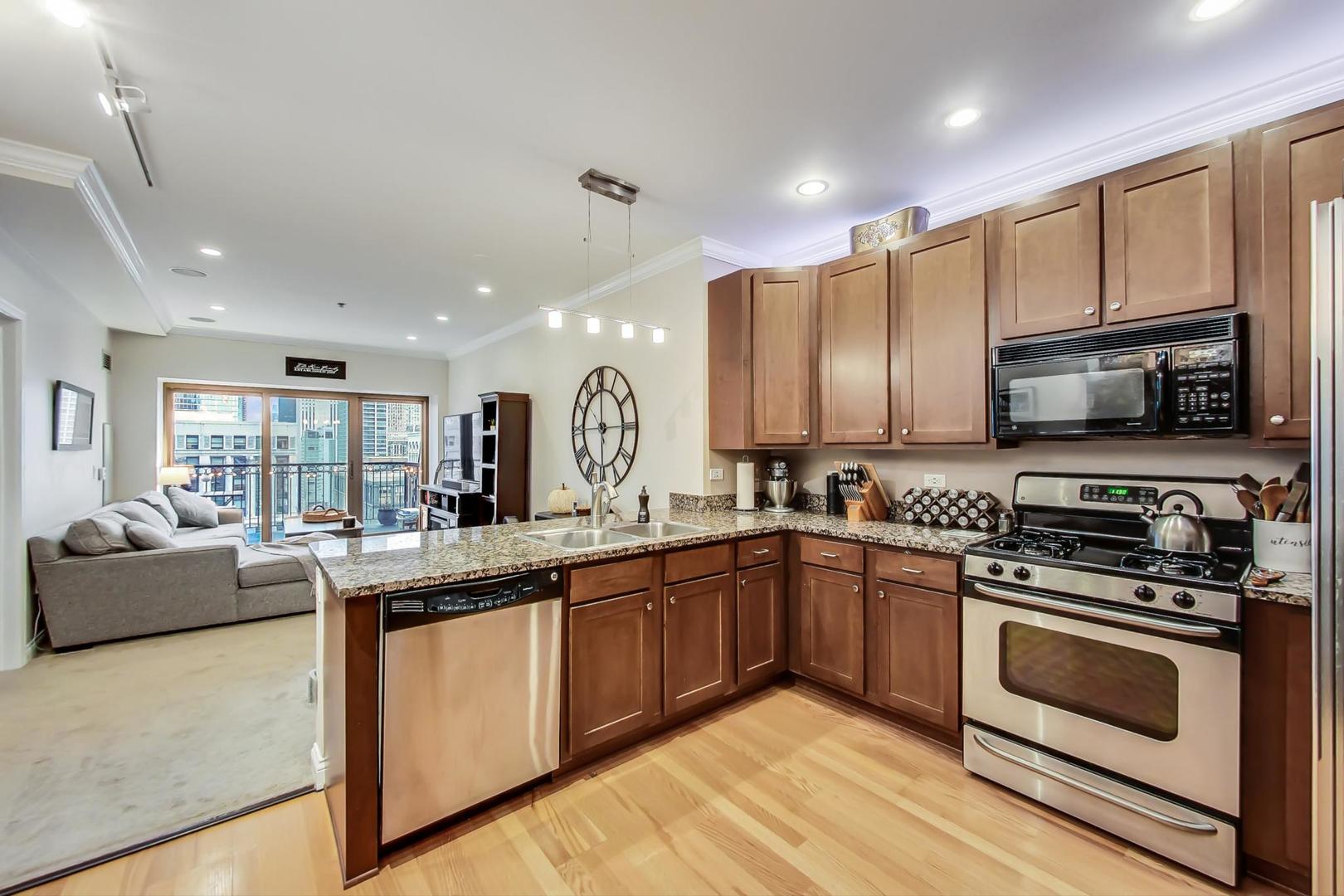 8 West Monroe Street, Unit 2008 Chicago, IL 60603 - Photo 6 of 18 a kitchen with stainless steel appliances granite countertop a stove top oven a sink dishwasher a refrigerator and white cabinets with wooden floor